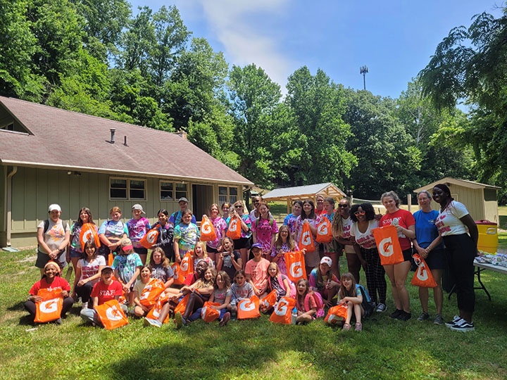 A group of Girl Scouts of various ethnicities smile at the end of an event.