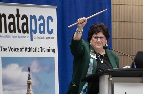 Past District 9 Director Marisa Brunett waves a drum stick before her NATAPAC keynote honoring Chuck Kimmel